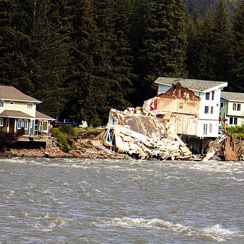 Una casa cuelga sobre el borde de un río erosionado después de que parte de la casa vecina cayera al río Mendenhall en Juneau, Alaska.