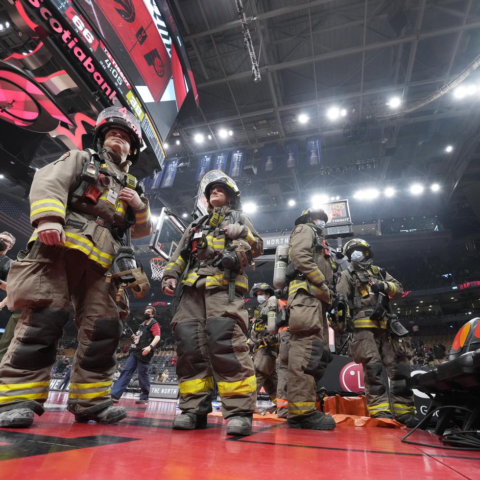 Los bomberos intervienen ante un incendio en un altavoz que obligó a suspender el partido del sábado 26 de marzo de 2022, entre los Pacers de Indiana y los Raptors en Toronto (Frank Gunn/The Canadian Press via AP)