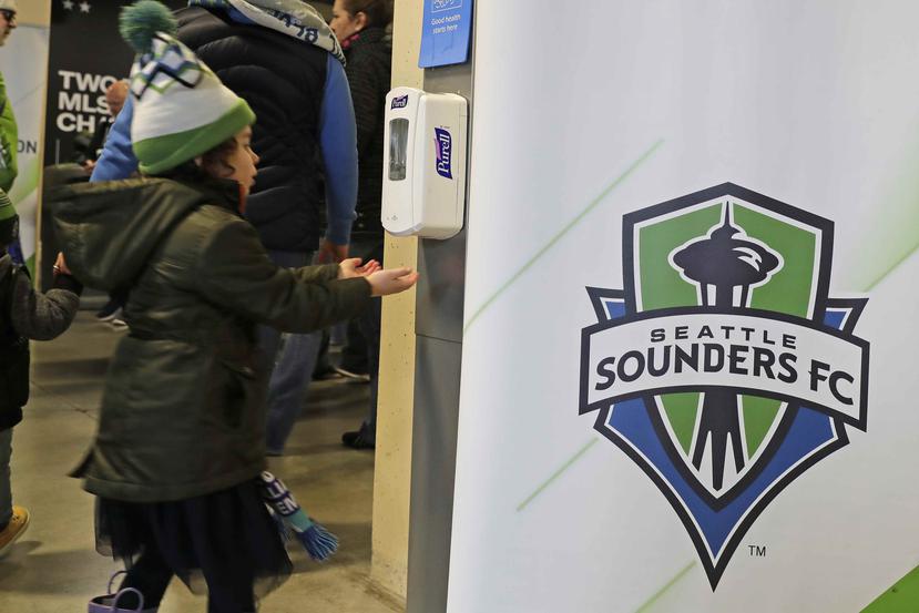 Una joven fanática del equipo de fútbol Seattle Sounders FC se desinfecta las manos antes de entrar al recinto para disfrutar del partido. (AP / Ted S. Warren)