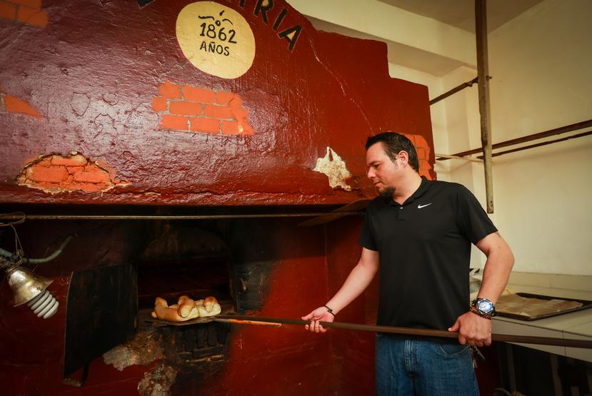 Edwin Ortiz, owner of La Patria, takes the famous bread out of the oven.