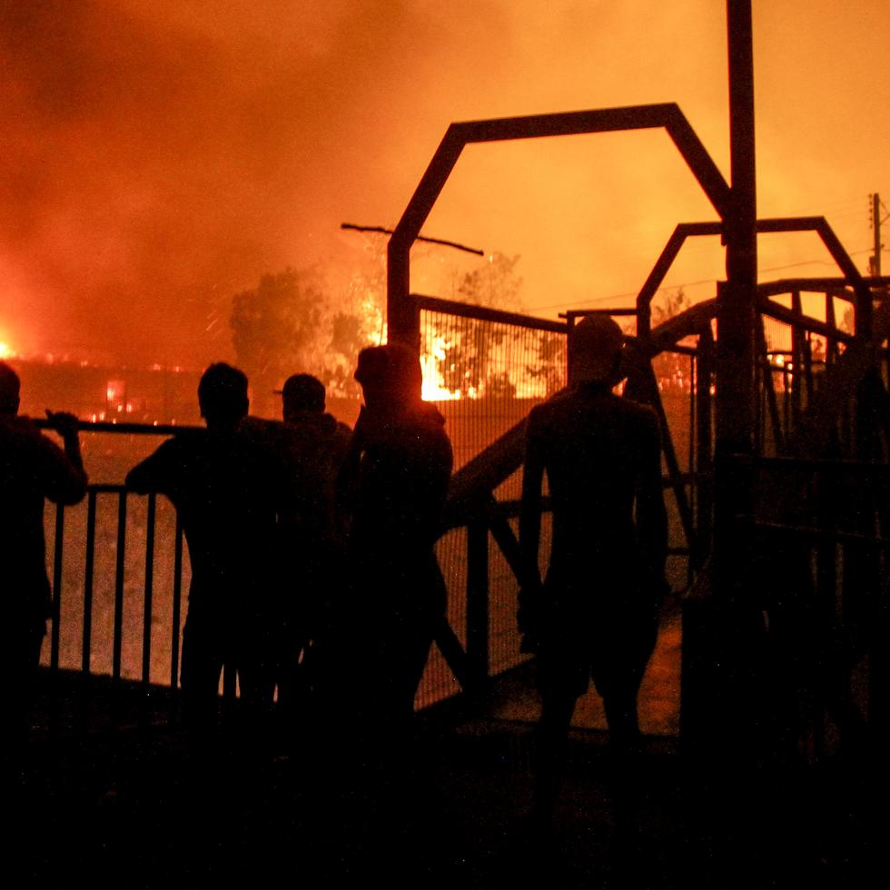 Un grupo de vecinos observa mientras las llamas devoran edificios en Viña del Mar, Chile, el 2 de febrero de 2024.