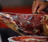 Un experto cortador trabaja con un jamón ibérico en una feria especializada en Villanueva de Córdoba (España).
