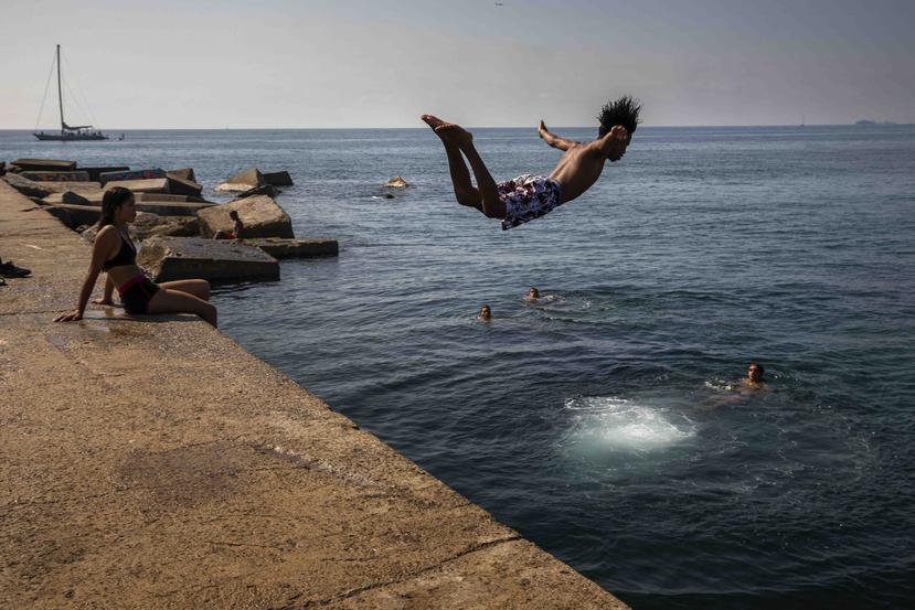 Esta foto de archivo del jueves 25 de julio del 2019 resalta a un niño lanzándose al mar en una playa de Barcelona, España. (AP)
