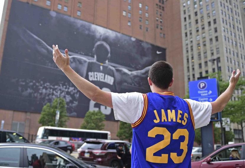 Un fanático de LeBron James se toma una foto junto al gigante afiche del astro de la NBA en Cleveland. (AP)
