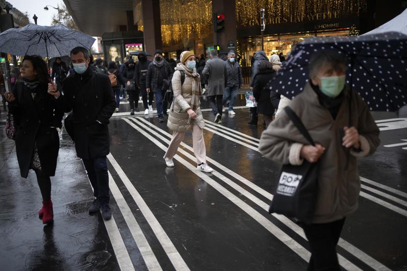 Unas personas con cubrebocas por el coronavirus caminan por una calle de París.