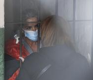 Standing behind bars, Bolivia's former interim President Jeanine Anez speaks to an unidentified woman at a police station jailhouse, in La Paz, Bolivia, Saturday, March 13, 2021. The conservative interim president who led Bolivia for a year was arrested Saturday as officials of the restored leftist government pursue those involved in the 2019 ouster of socialist leader Evo Morales, which they regard as a coup, and the administration that followed. (AP Photo/Juan Karita)