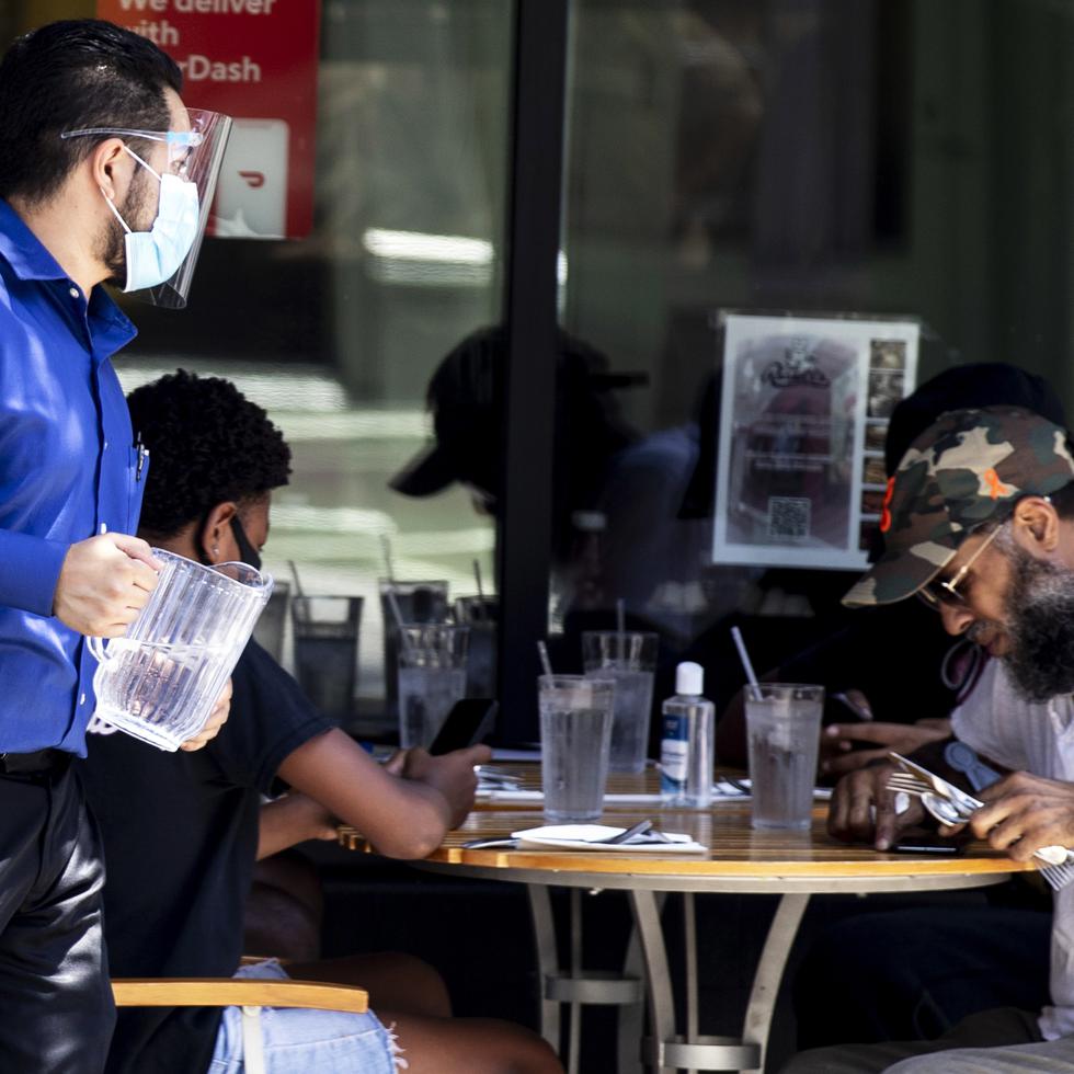 Un mesero usa una mascarilla mientras atiende a los comensales en un restaurante en California. /ArchivoEFE/EPA/ETIENNE LAURENT

